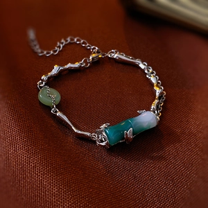 Detailed shot of silver bamboo-style chain bracelet with green faux jadeite stone