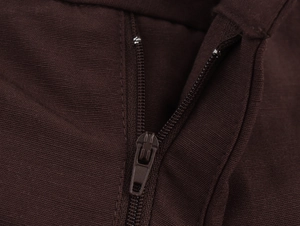 Detailed macro view of the hidden zipper closure on dark brown pleated wide leg trousers
