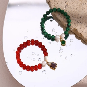 Detail of beaded bracelets with malachite and agate beads on a reflective water surface