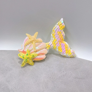 Detailed view of pink and yellow sequined mermaid tail hair clip with starfish and shell