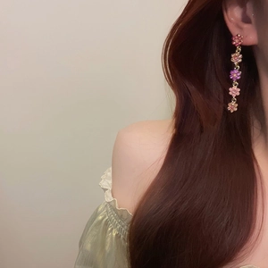 Détail de boucles d'oreilles pendantes fleurs avec dégradé de rose et cristaux brillants