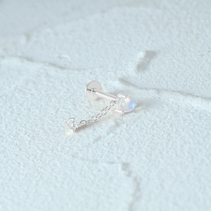 Macro detail of S925 silver piercing stud with moonstone and a hanging zircon stone