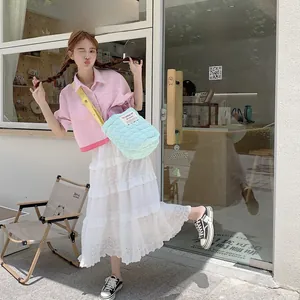 Sac à bandoulière matelassé bleu clair porté avec une chemise rose et une jupe en dentelle
