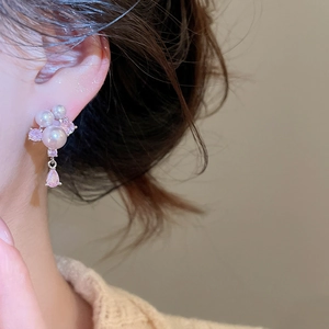 Close-up of elegant pearl and pink zircon teardrop earrings on model's ear