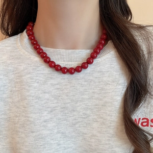 Close-up of minimalist dark red glass beaded necklace worn on a white shirt
