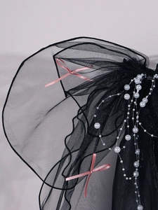 Close-up of black mesh veil featuring delicate pink bows and white pearl bead accents
