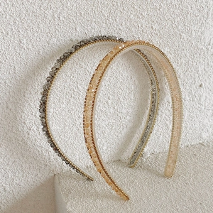Detail of slim crystal beaded headbands in grey and champagne on stone surface