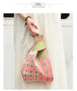Detail of pink and green knitted wrist bag showing thick woven texture on model's hand