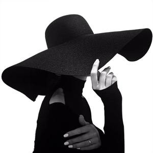 Artistic silhouette of a black wide brim straw sun hat with elegant wavy edges