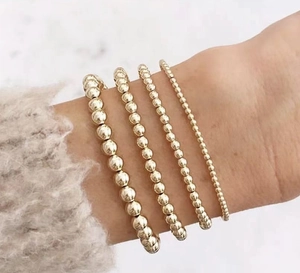 Close-up of four-piece set golden stainless steel bead bracelets on female model wrist