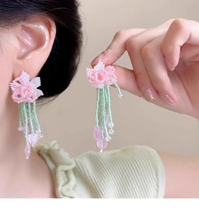 Detailed close-up of handmade pink floral beaded earrings with light green bead tassels