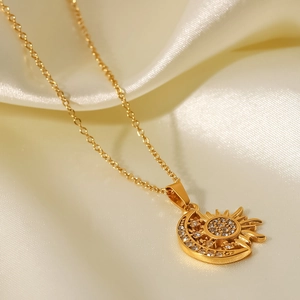 Close-up of 18k gold plated sun and moon pendant with white crystals on silk