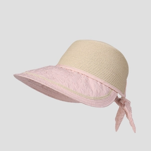 Close-up of beige straw sun hat featuring a pink bow and wavy textured fabric brim