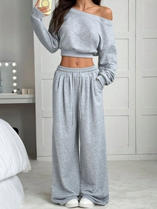 Detail eines grauen schulterfreien Sweatshirts und einer weiten Hose mit Kordelzug