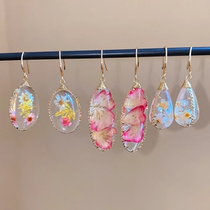 Vista detallada de pendientes de resina hechos a mano con flores secas reales y oro