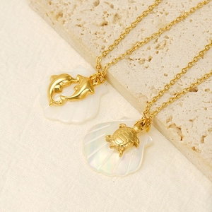 Detailed macro view of 18K gold dolphin and turtle pendants with shell inlay on stone