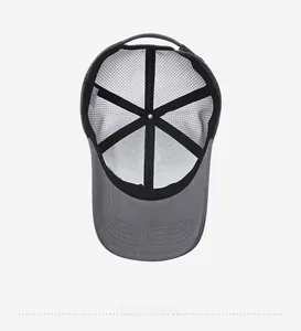 Detail view of grey trucker hat featuring breathable black mesh and interior wash label