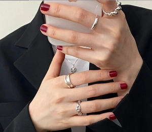 Close-up of minimalist S925 sterling silver rings and necklace worn on hands and neck