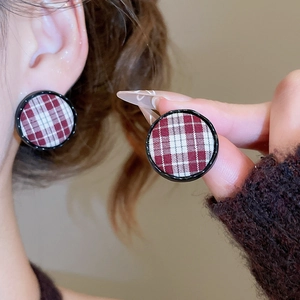 Detail shot of red and white plaid fabric earrings on a round black textured frame