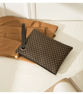 Detail of crocodile embossed brown briefcase with gold zipper and stylish wrist strap