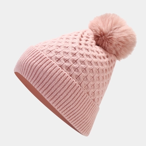 Detail of pink knitted beanie with soft pom-pom showing premium winter cable-knit texture
