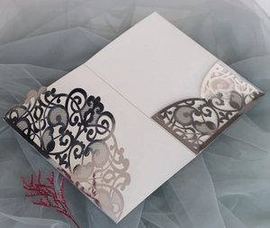 Close-up of white laser-cut wedding invitation sleeve with silver floral patterns