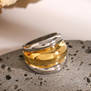 Polished chunky ribbed ring in two-tone gold and silver on a textured stone surface