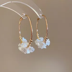 Elegant gold hoop earrings featuring acrylic white flower petals and golden bead accents