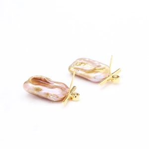 Elegant gold baroque pearl stud earrings with sparkling zircon accents on white background