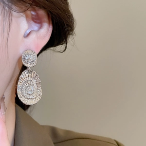 Detailed view of silver oval earrings with radiant spiral texture worn by a model