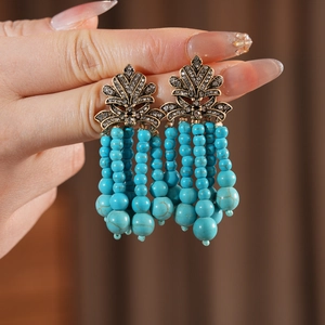 Detail von Vintage-Boho-Ohrringen mit türkisfarbenen Perlen und Kristall-Blattsteckern