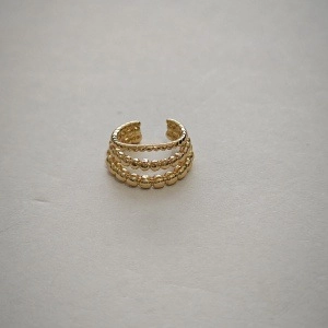Vue macro d'un earcuff doré à trois couches avec un design vintage en forme de C