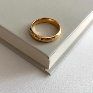 Minimalist S925 sterling silver ring with polished gold finish shown on a book corner