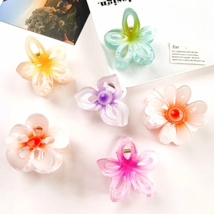 Detailed top view of various colorful gradient frangipani flower hair claws on white background