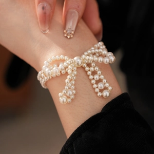 Nahaufnahme des weißen Perlenarmbands mit Schleife am Handgelenk in elegantem Design
