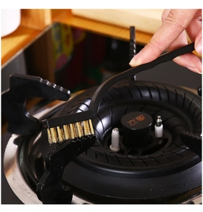 Detail of a brass wire brush cleaning grease from a kitchen gas stove burner