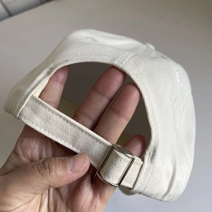 Close-up of cotton baseball cap with adjustable strap and silver metal buckle detail