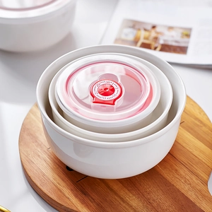 Three-piece stackable white ceramic food storage bowls with date dial lids on wood board