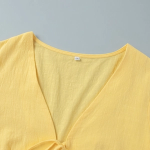 Detail of yellow V-neck top showing cotton linen texture and tie-neck design