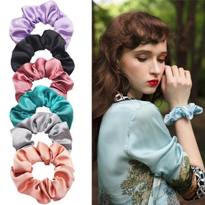 Close-up of colorful silk satin hair scrunchies and model wearing a soft wrist tie