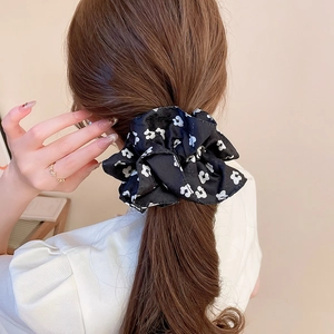 Detail of floral black scrunchie worn on a low ponytail with elegant fabric texture