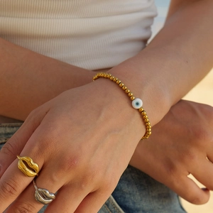 Bracelet à perles en acier doré 18k avec œil protecteur et bagues lèvres portés