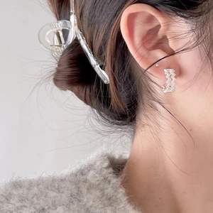 Close-up of silver water wave earrings with pavé zircons worn by a female model