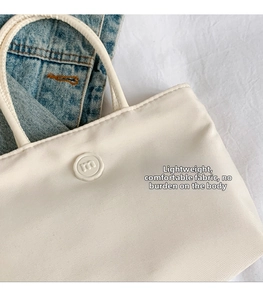 Détail du sac fourre-tout en nylon blanc cassé avec logo m circulaire sur tissu léger