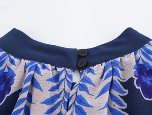 Detail view of round neckline with two black buttons on blue floral chiffon dress