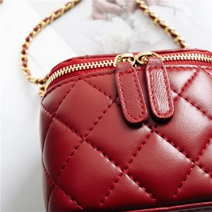 Detail shot of the red quilted leather bag showing gold zippers and metal chain strap