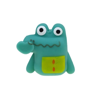 Close-up of green TPR crocodile finger puppet toy with big eyes and yellow pocket
