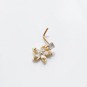Macro shot of gold floral nose stud featuring clear zircon stones and a curved L-shaped bar