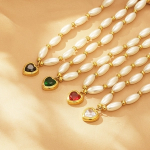 Elegant gold pearl necklace with four heart-shaped crystal pendants in varied colors