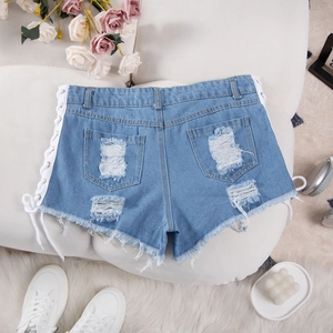 Dettaglio in piano di pantaloncini di jeans azzurri con strappi e lacci bianchi laterali